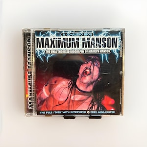 May include: A CD-audio biography of Marilyn Manson, titled "Maximum Manson." The CD case features a dramatic image of Manson with the text "The Unauthorised Biography of Marilyn Manson." Includes interviews and a free mini-poster.