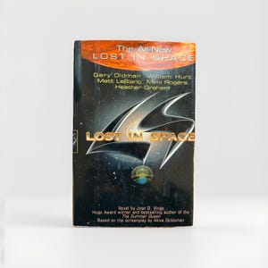 May include: A hardcover book titled "The All-New Lost in Space" with a dark cover featuring a silver and black design and the title in gold. The book's cover also lists the names of the actors from the movie.