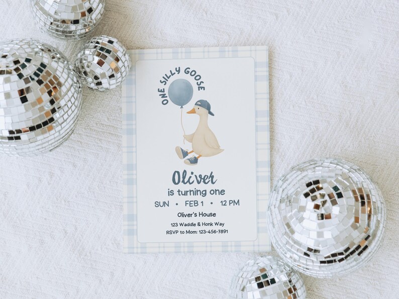 Op de afbeelding: Een verjaardagsuitnodiging met een cartoon gans die een ballon vasthoudt. De uitnodiging heeft een blauwe geruite rand en bevat de tekst "One Silly Goose", "Oliver is turning one" en evenementdetails. Zilveren discoballen zijn verspreid rond de uitnodiging.
