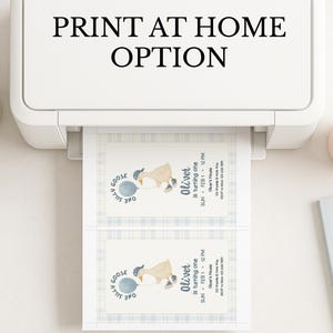 Op de afbeelding: Een witte printer met de tekst "PRINT AT HOME OPTION" drukt twee uitnodigingen af. Elke uitnodiging toont een cartoon gans met een blauwe ballon en de tekst "Oliver is turning one". Een kleine plant en een roze mok zijn zichtbaar.