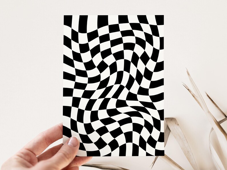 Puede incluir: Una tarjeta rectangular con un patr&oacute;n de tablero de ajedrez en blanco y negro distorsionado y ondulado. La tarjeta es sostenida por una mano sobre un fondo neutro. El patr&oacute;n de tablero de ajedrez crea una ilusi&oacute;n visual.