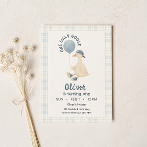 One silly goose boy first birthday invitation mockup on neutral stone background, blue plaid border and cream textured card featuring a cute goose in sneakers and a backwards cap holding a blue balloon, text reading “One Silly Goose” and “Oliver is turning one,” modern minimalist design for editable Canva template, printable invite, digital download baby boy birthday party.