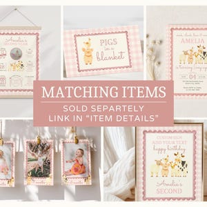 May include: A collection of pink and white themed birthday party decorations. Includes a wall hanging, cards, and framed signs with illustrations of farm animals and the text "Amelia's Second Year" and "Pigs in a blanket".