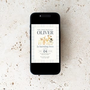 May include: A smartphone displays a birthday invitation with a farm animal theme. The invitation features the name "Oliver" above the text "is turning two." The design includes illustrations of a sheep, cow, and pig, with the date and time of the party.