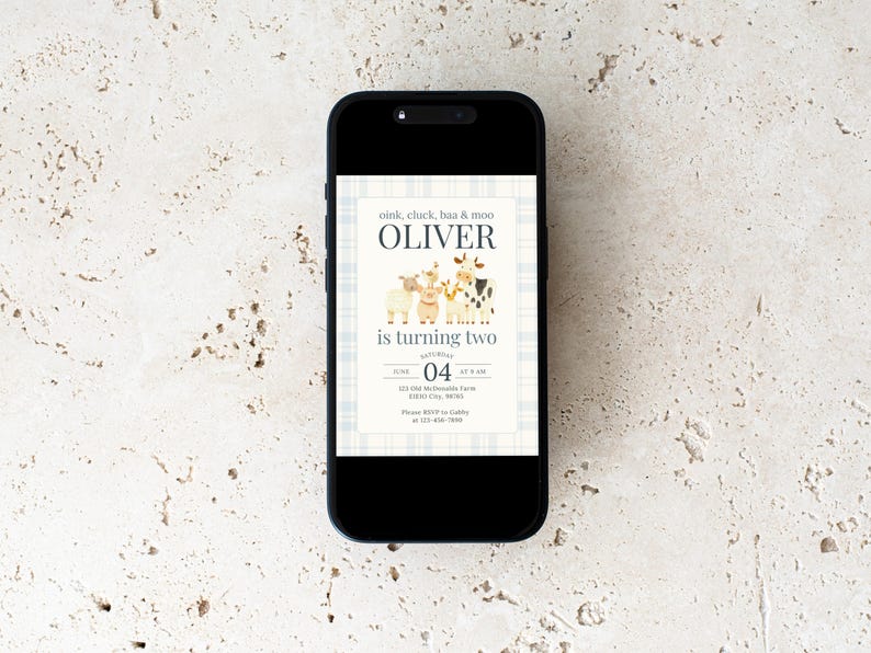 May include: A smartphone displays a birthday invitation with a farm animal theme. The invitation features the name "Oliver" above the text "is turning two." The design includes illustrations of a sheep, cow, and pig, with the date and time of the party.