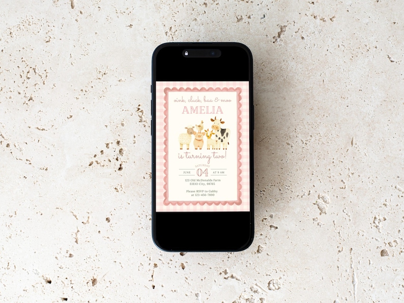 May include: A smartphone displays a pink and cream-colored birthday invitation. The invitation features illustrations of farm animals and the text "Amelia is turning two!" with the date June 4th.