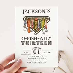 May include: A white invitation card with the text "JACKSON IS O-FISH-ALLY THIRTEEN". The card features a graphic of colorful fishing lures. The date is June 04 at 9 AM. Includes address and RSVP information.