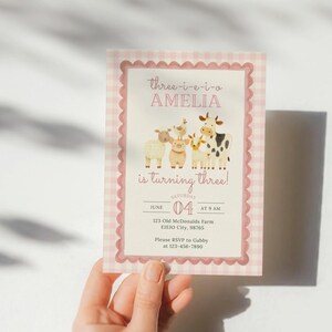 May include: A pink and white gingham-patterned invitation with a scalloped border. The invitation features the text "three-i-e-i-o AMELIA is turning three!" and illustrations of farm animals. The date is June 4th.