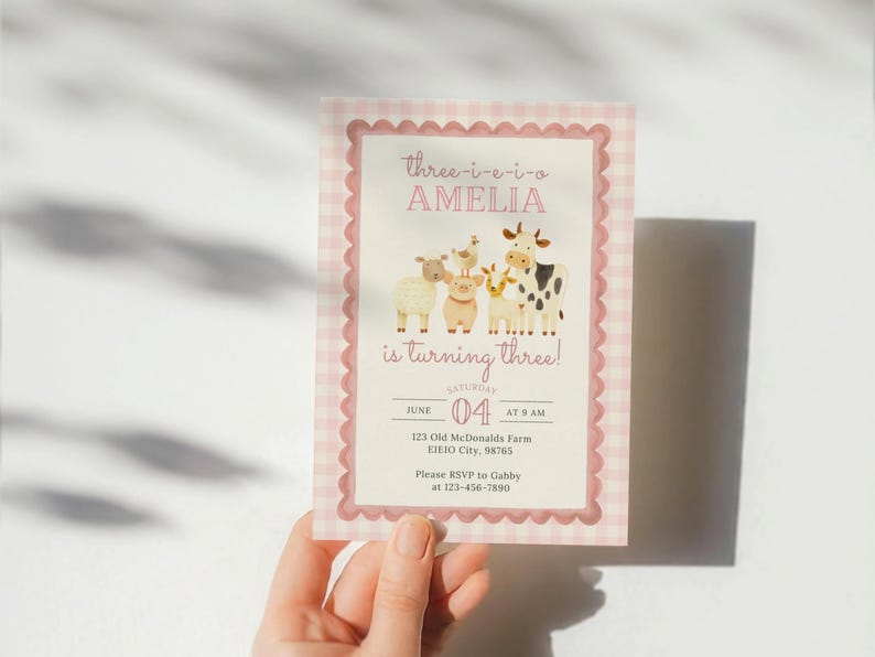 May include: A pink and white gingham-patterned invitation with a scalloped border. The invitation features the text "three-i-e-i-o AMELIA is turning three!" and illustrations of farm animals. The date is June 4th.