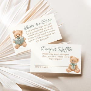 May include: Two cream-colored baby shower invitation cards. One card reads "Books for Baby" and features a teddy bear reading a book. The other card reads "Diaper Raffle" and has a teddy bear with a blue bow.