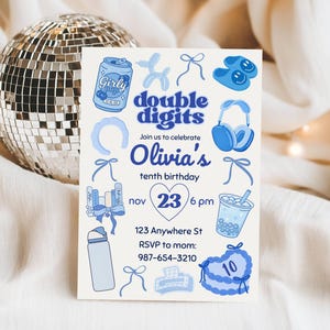 May include: A light blue birthday invitation with the text "double digits" and "Olivia's tenth birthday." The invitation includes illustrations of a soda can, balloons, headphones, and a cake. The date is 23rd November at 6 pm.