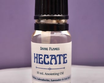 May include: A small glass bottle of anointing oil with a black cap. The label reads "Divine Flames Hecate 10 mL Anointing Oil." The background is a solid purple color. The bottle contains a clear liquid.