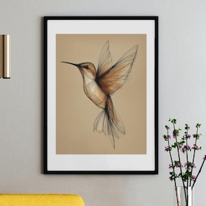 May include: A framed pencil sketch of a hummingbird in flight. The bird is rendered in shades of brown and tan, with delicate wing details. The artwork is set against a neutral background and framed in black, creating a minimalist aesthetic.