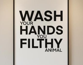 Puede incluir: Un cuadro en blanco y negro enmarcado para el baño con el texto "WASH YOUR HANDS YOU FILTHY ANIMAL". El cuadro está colgado sobre un lavabo blanco con un grifo cromado y una pequeña planta suculenta en maceta.