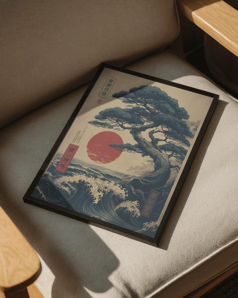 May include: Framed art print with a Japanese design. It shows a stylized tree, a red sun, and ocean waves. The colour scheme includes blue, red, and beige. The print is in a black frame, suitable for various interior styles.