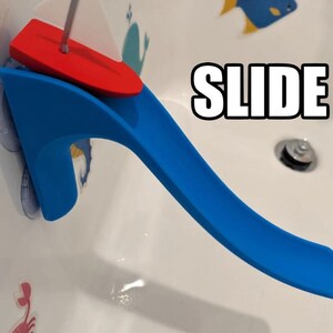 May include: A blue and red plastic bath toy slide with the word "SLIDE" in large white letters. The slide is attached to the side of a bathtub with suction cups. A red boat-shaped piece sits at the top of the slide.