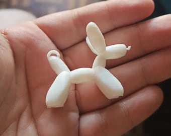 Puede incluir: Un pequeño dije blanco impreso en 3D con forma de perro globo. El dije tiene forma de perro, con su cuerpo y patas formadas por formas redondeadas. Tiene un pequeño lazo en la parte superior para sujetarlo a un llavero o collar.