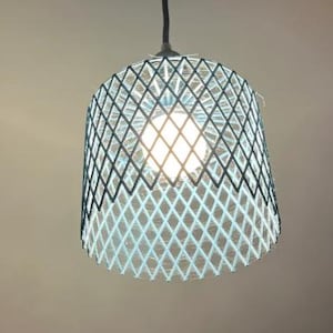 May include: A pendant light with a diamond-patterned shade. The shade is a light blue and dark blue woven design. A light bulb is visible inside, emitting a warm glow. The fixture hangs from a black cord.