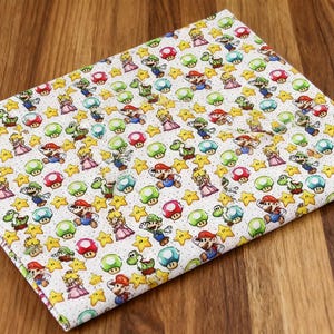 May include: White fabric with a colorful pattern featuring characters and icons from the Super Mario video game series. The design includes Mario, Princess Peach, mushrooms, stars, and other recognizable elements.