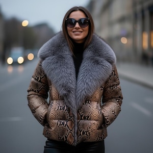 Può includere: Giacca trapuntata marrone e beige con motivo a pelle di serpente e ampio collo in pelliccia grigia. La giacca ha un collo alto e viene indossata sopra un dolcevita nero. La persona indossa occhiali da sole.