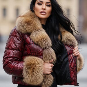 K&ouml;nnte beinhalten: Rote Pufferjacke mit Schlangenmuster und braunem Pelzkragen und -b&uuml;ndchen. Die Jacke ist mit einem Rei&szlig;verschluss versehen und hat ein schwarzes Futter. Das Model tr&auml;gt ein schwarzes Oberteil.