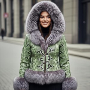 Könnte beinhalten: Grüne Jacke mit Schlangenmuster und großer Kapuze sowie Manschetten mit grauem Pelzbesatz. Die Jacke hat einen Reißverschluss und einen schwarzen Rollkragenpullover darunter. Der Pelzbesatz ist in einem helleren Grauton gehalten.