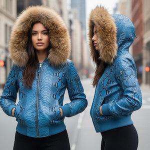 Puede incluir: Chaqueta bomber azul con estampado de piel de serpiente y capucha forrada de piel. La chaqueta tiene cierre de cremallera, puños de canalé y bolsillos. La modelo lleva pantalones negros. Una prenda de abrigo elegante.