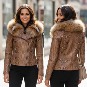 以下が含まれることがあります： ヘビ革模様と毛皮の襟が付いた茶色のレザージャケット。 ジャケットは斜めのジッパー開閉とジッパー付きの袖が特徴です。 モデルは黒いパンツを履き、ベージュのハンドバッグを持っています。