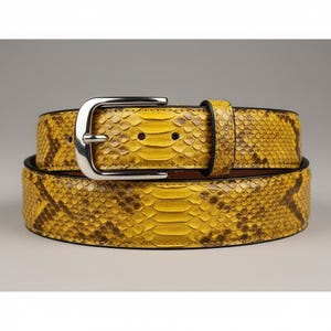 May include: A yellow and brown snakeskin belt with a silver buckle. The belt is made of genuine snakeskin and has a textured surface. The belt is a classic accessory.