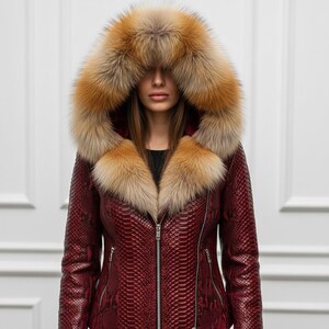 Puede incluir: Chaqueta de cuero burdeos con estampado de piel de serpiente, con una gran capucha ribeteada con piel marr&oacute;n y beige. La chaqueta tiene cierre de cremallera y bolsillos laterales, ofreciendo una opci&oacute;n de abrigo elegante y c&aacute;lida.