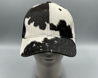 Boné de beisebol artesanal em couro bovino, com estampa de pelo de vaca em preto e branco, ajustável.