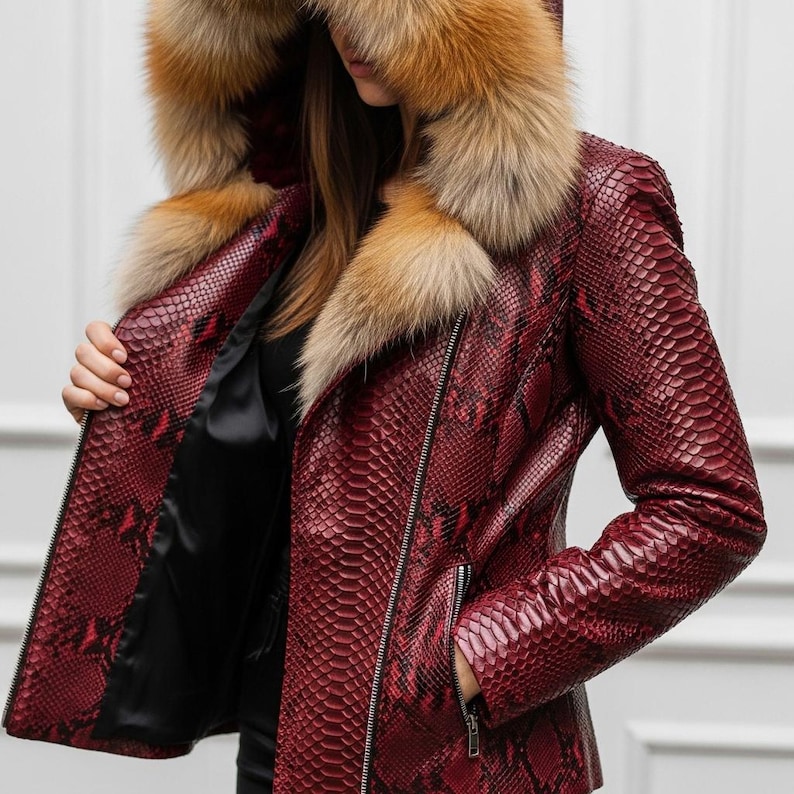 Puede incluir: Chaqueta de cuero roja con estampado de piel de serpiente y capucha con ribete de piel. La chaqueta tiene cierre de cremallera y forro de sat&eacute;n negro. El ribete de piel es una mezcla de colores marr&oacute;n y beige.