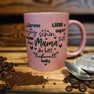 Glitzertasse in Rosa mit Text Mama, super, Liebe, Herzen, mutig etc. in Herzform auf der Tasse aufgebracht