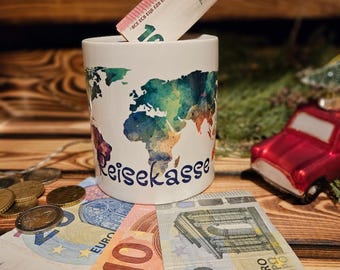 May include: A white ceramic travel fund mug with a world map design and the word "Reisekasse". A ten Euro bill is inserted into the mug, with additional Euro bills and coins scattered around. A red car ornament is in the background.