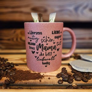 Glitzertasse in Rosa mit Text Mama, super, Liebe, Herzen, mutig etc. in Herzform auf der Tasse aufgebracht