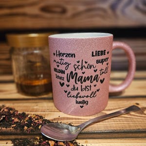 Glitzertasse in Rosa mit Text Mama, super, Liebe, Herzen, mutig etc. in Herzform auf der Tasse aufgebracht