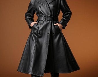 May include: A black leather trench coat with a double-breasted design, a belted waist, and a flared skirt. The coat features a classic collar, epaulets, and long sleeves. The model is wearing black boots. The coat is approximately knee-length.