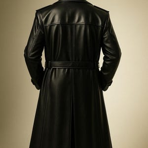 May include: A long, black leather coat with a belted waist and a split back. The coat has a classic trench coat design with a notched collar and shoulder epaulets. The coat is made of a smooth, shiny leather material.
