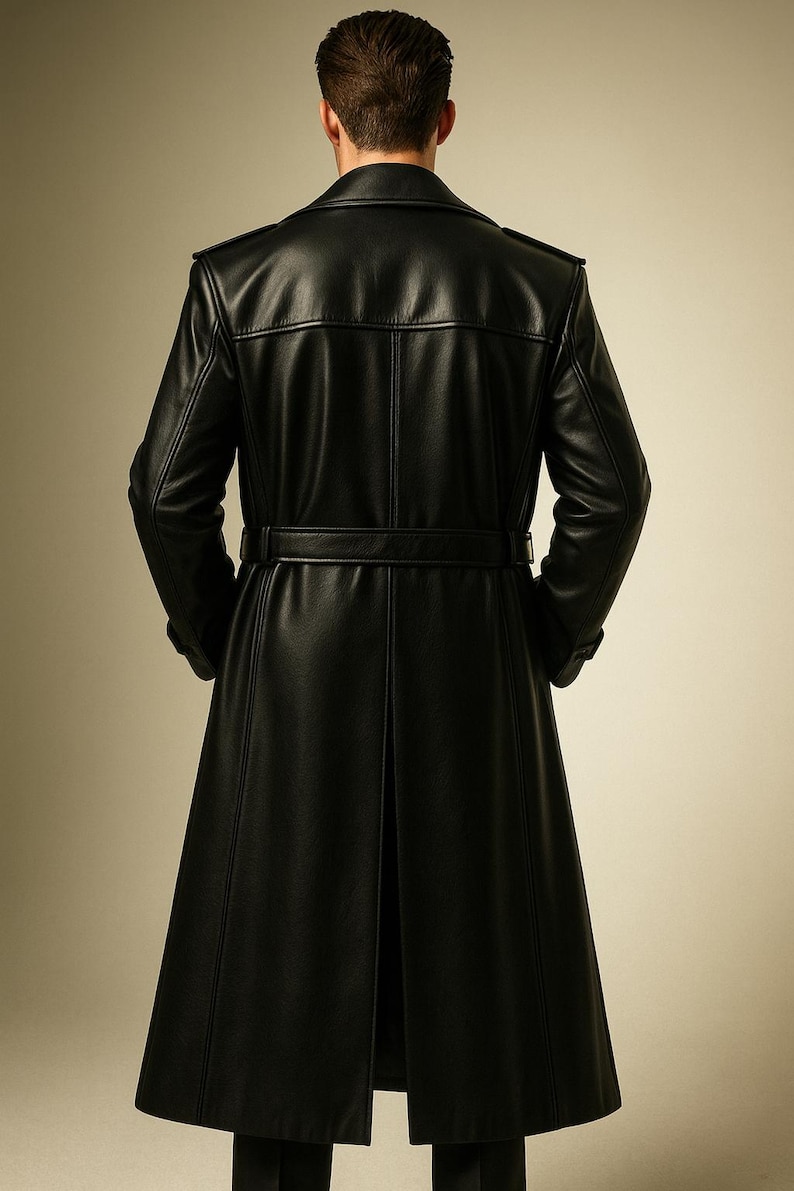 May include: A long, black leather coat with a belted waist and a split back. The coat has a classic trench coat design with a notched collar and shoulder epaulets. The coat is made of a smooth, shiny leather material.
