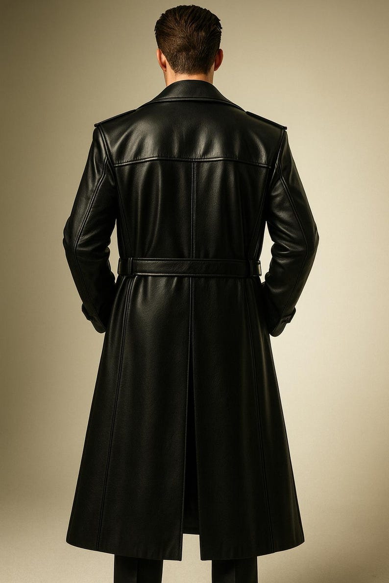 May include: A long, black leather coat with a belted waist and a split back. The coat has a classic trench coat design with a notched collar and shoulder epaulets. The coat is made of a smooth, shiny leather material.