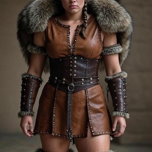 May include: A brown leather costume with fur trim, featuring a sleeveless top, skirt, and arm cuffs. The outfit includes a fur collar and leg warmers. The costume is detailed with metal studs and a belt.