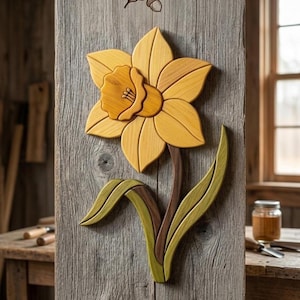 May include: A wooden daffodil wall art piece. The flower is crafted from various shades of wood, featuring yellow petals, a brown stem, and green leaves. The artwork is mounted on a weathered wooden plank, showcasing the natural wood grain.