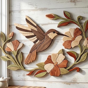 May include: A wall-mounted wooden art piece featuring a hummingbird in flight surrounded by floral vines. The design uses various wood tones including light, medium, and dark brown, along with muted green accents for the leaves and petals.