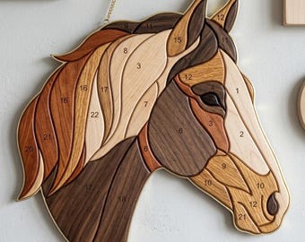 May include: A wall-hanging horse head plaque crafted from segmented pieces of light, medium, and dark wood. The design features a flowing mane and numbered sections throughout the surface, suspended by a thin gold-toned metal chain at the top.