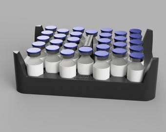 May include: A black tray holds multiple small glass vials with white labels and blue caps. The vials are arranged in rows. The tray has a rectangular shape with raised sides. The background is a solid gray color.