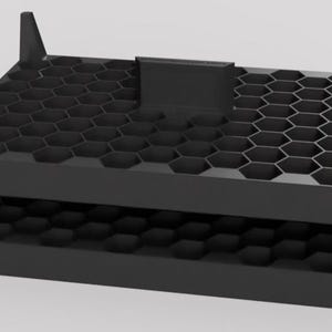May include: A black, rectangular storage organizer featuring a two-tier design with a honeycomb-patterned grid. The structure includes four vertical corner supports and a central divider on the top level, providing multiple hexagonal compartments.