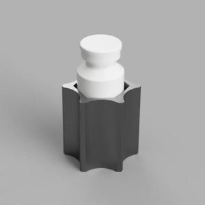 Op de afbeelding: Een donkergrijze, stervormige houder met een gladde, matte afwerking, voorzien van een cilindervormig wit inzetstuk aan de bovenkant. Het object heeft een opvallend zespuntig stervormig silhouet met verticale zijden en een platte basis.