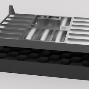 Op de afbeelding: Een donkergrijze rechthoekige opbergorganizer met een metallic zilveren bovenoppervlak met meerdere verzonken sleuven en compartimenten. Het basisgedeelte bevat een zwart honingraatrooster. De tekst printandprosper.store is zichtbaar op de bovenkant.