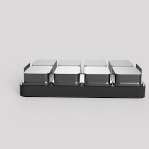 May include: A black and silver rectangular object with eight individual compartments. The compartments have a silver top and a black base. The object is on a white background.