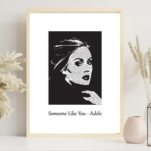Puede incluir: Impresión artística en blanco y negro de un retrato de mujer con texto que llena la imagen. La impresión está en un marco de madera clara y presenta el texto "Someone Like You - Adele" en la parte inferior.